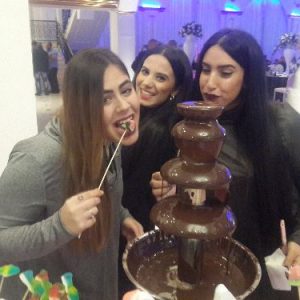 3 בנות אוכלות מתוך מזרקת שוקולד