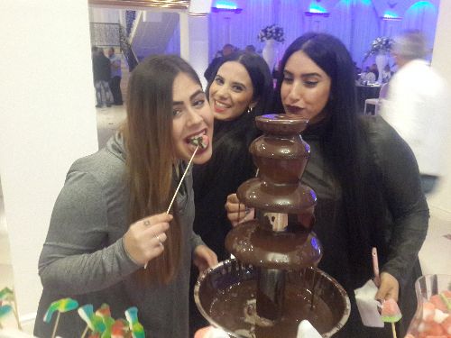 3 בנות אוכלות מתוך מזרקת שוקולד