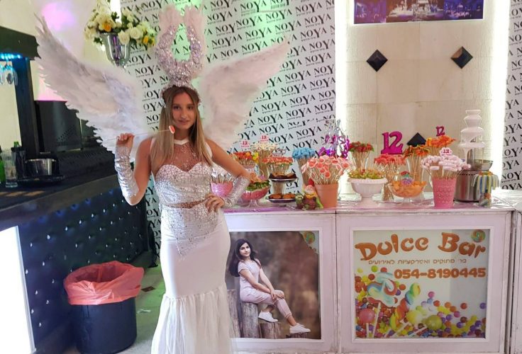 תמונה של אישה עומדת ליד בר מתוקים לבת מצווה